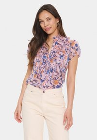 Gėlių palaidinė su volaniniu iškirpimu rožinės, mėlynos ir oranžinės spalvų atspalvių. Trumpomis rankovėmis, su sagų uždarymu, su subtilia, lengva tekstūra.