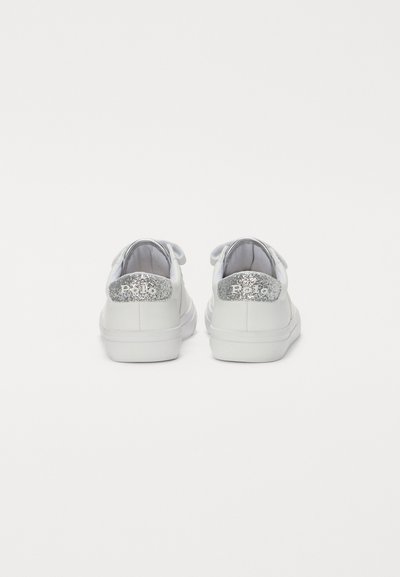 Vita sneakers med en slät läderovandel, en silver-glittrig hälflik och traditionella snören. Sulan är platt och texturerad.