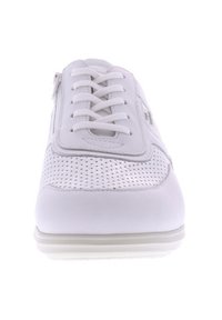 White sneaker with perforated upper, flat laces, and side zipper. Features smooth, flexible material and a cushioned sole.