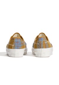 Textured yellow and blue plaid canvas shoes with a low profile and white rubber soles. Slip-on design with no visible laces or hardware.