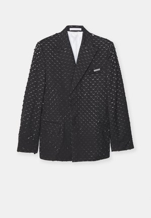 Melna blazer jaka ar teksturētu virsmu, kurā ir atkārtoti pusmēness formas, divas sānu kabatas un krūšu kabata. Oderēts iekšpuse.