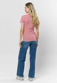 Sarkana un balta svītrota īsām piedurknēm t-krekls, apvienots ar platām zilo džinsu biksēm, kurām ir brīvs piegriezums un neliela nolietojuma pazīmes. Baltas sporta apavi.