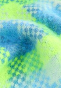 Mäkká, pubertná tkanina s tkaným vzorom v jasnej neónovej zelenej, svetlomodrej, bielej a námorníckej modrej farbe, vystavená s prehnutím a detailmi textúry.