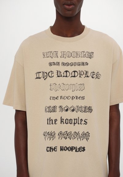 Beez värvi ülekaaluline t-särk, mis on valmistatud puuvillast ja millel on erinevad stiliseeritud tekstitooted "The Kooples" erinevates fontides ja suurustes.