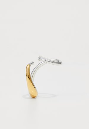 Silver and gold-tone adjustable ring featuring a smooth, curving design with a polished finish. Notable for its contrasting metallic colors.