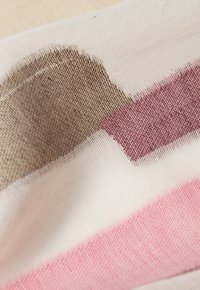 Tessuto di cotone con motivi astratti nelle tonalità di marrone, rosa e bianco. Morbida texture con dettagli tessuti e variazioni di colore.