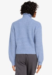 Světle modrý, robustní pletený svetr s vysokým límcem a širokými rukávy. Hladký vzor a zkrácený lem. Zobrazená zadní strana.