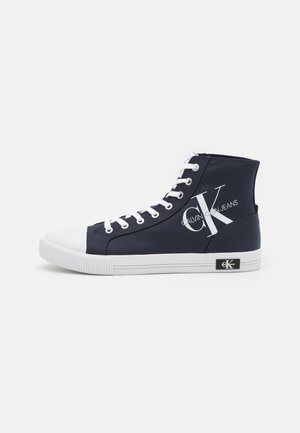 Wysokie granatowe trampki z białym gumowym noskiem, sznurowadłami i podeszwą, z dużym logo Calvin Klein Jeans po boku.