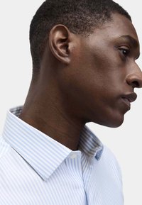 Blauw en wit gestreept overhemd met een button-down kraag, frisse stof en een gladde textuur. Zijaanzicht, waarbij de details zichtbaar zijn.