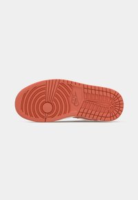Semelle de sneaker en caoutchouc orange avec des motifs de crantage circulaires et linéaires. Logo Nike centré. Surface texturée pour l'adhérence et la traction.