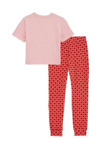 T-shirt di cotone rosa abbinata a pantaloni da pigiama rossi con un motivo ripetuto di cuori bianchi su una griglia. Tessuto morbido, vestibilità comoda.