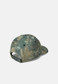 Gorra de béisbol de camuflaje en verde y marrón, hecha de tela, con visera curvada y correa ajustable en la parte posterior. Presenta costuras y orificios de ventilación.