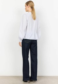 Světle modrá pruhovaná blůza s nabíranými rukávy a peplum pasem, v kombinaci s tmavými džínovými zvonovými kalhotami. Hladká textura, volný střih.
