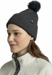 Dark gray knitted beanie with a ribbed texture and a pom-pom on top. Features a small round logo tag on the side.