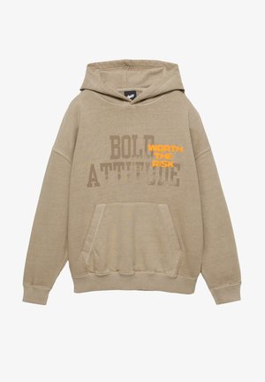 Beżowa bluza z kapturem wykonana z miękkiego materiału, z kangurzą kieszenią. Na przodzie znajduje się wyraźny nadruk z tekstem: "BOLD ATTITUDE" oraz "WORTH THE RISK."