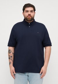 Navyblauwe poloshirt gemaakt van katoen, met een kraag, een twee-knopen sluiting en een klein logo op de linkerborst. Zachte textuur en korte mouwen.