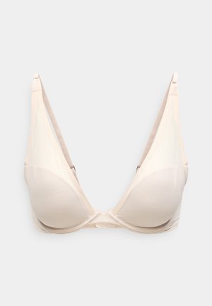 Sottile reggiseno beige wireless con tessuto liscio, design a scollo a v, coppe sagomate, spalline regolabili e logo del marchio discreto sul lato.