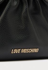 Μαύρη δερμάτινη τσάντα με σχεδιασμό με πτυχώσεις, διαθέτοντας ανάγλυφη υφή και χρυσό λογότυπο "LOVE MOSCHINO" στο κάτω μέρος.