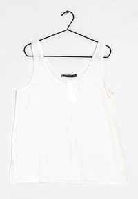 Top bianco senza maniche realizzato in tessuto liscio, con scollo rotondo e spacchi laterali per una maggiore ventilazione. Appeso a un gancio nero.