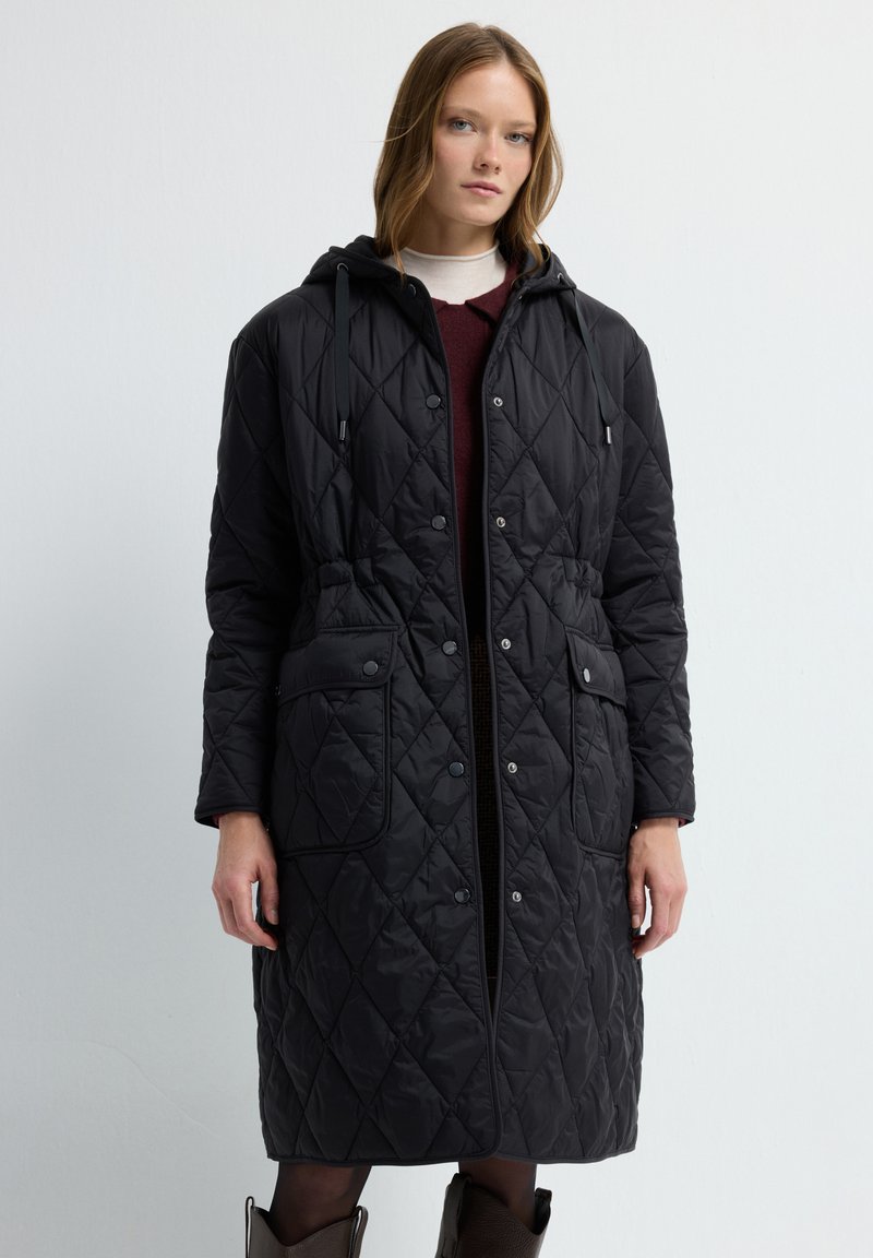 Czarna pikowana długa kurtka z kapturem, posiadająca zapięcie na guziki z przodu, sznurki oraz dwie boczne kieszenie. Gładki, lekki materiał.