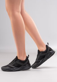 Schwarze Sportschuhe aus Mesh- und synthetischen Materialien. Dicke Gummisohle und gepolstertes Design. Mit einer Lasche an der Ferse für einfaches An- und Ausziehen ausgestattet.
