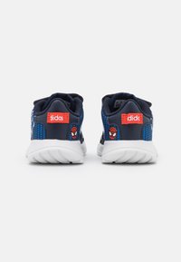 Baskets de sport bleues avec des graphismes de Spiderman, une tige texturée et des semelles blanches. Présente une étiquette logo rouge sur le talon.