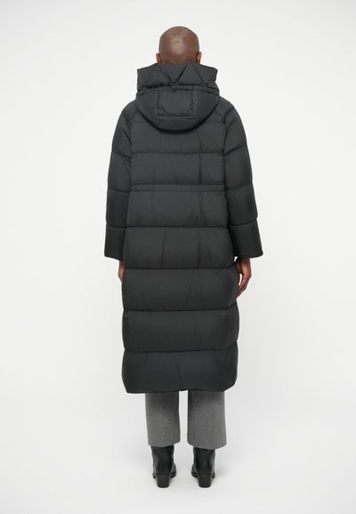 Μαύρο μακρύ παλτό από πούπουλο με κουκούλα, που διαθέτει οριζόντιες ραφές και χαλαρή εφαρμογή. Κατασκευασμένο από ελαφρύ, θερμικά μονωμένο υλικό.