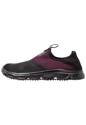Chaussure de sport à enfiler avec tige en mesh respirant noir et violet foncé et semelle noire texturée, avec une boucle de traction sur la languette.