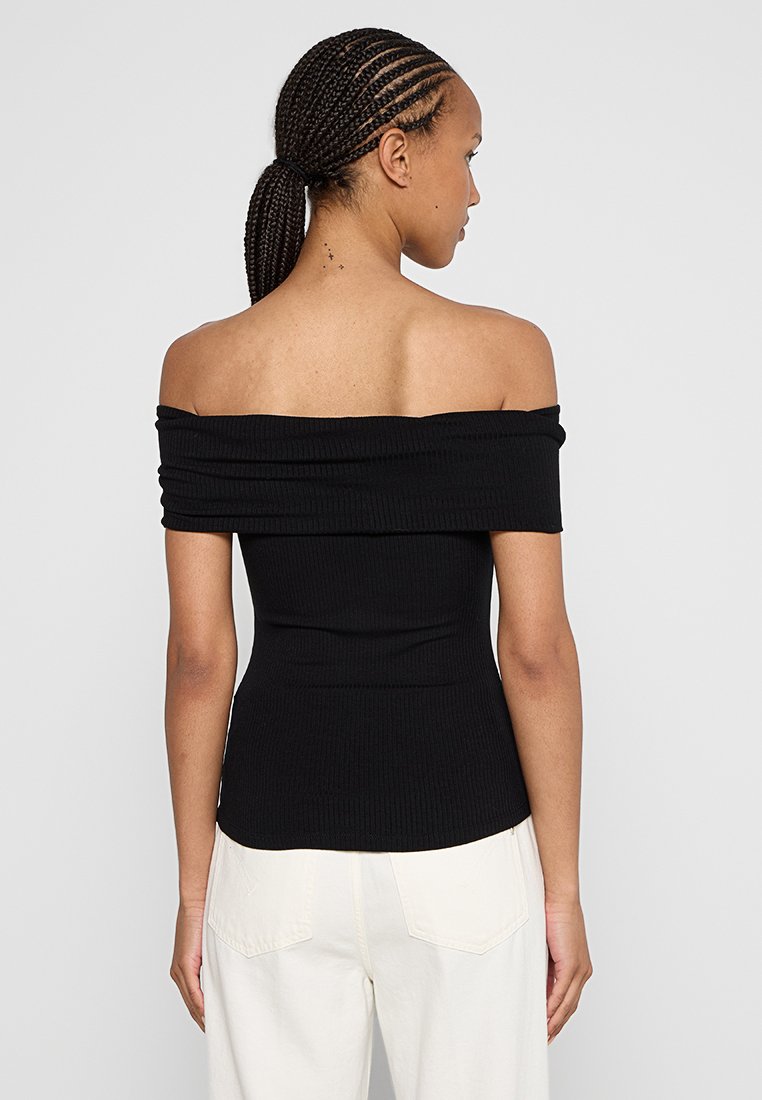 Top noir à épaules dénudées en rib carrée, avec une silhouette ajustée, présentant un tissu plié au niveau du col et une texture lisse.
