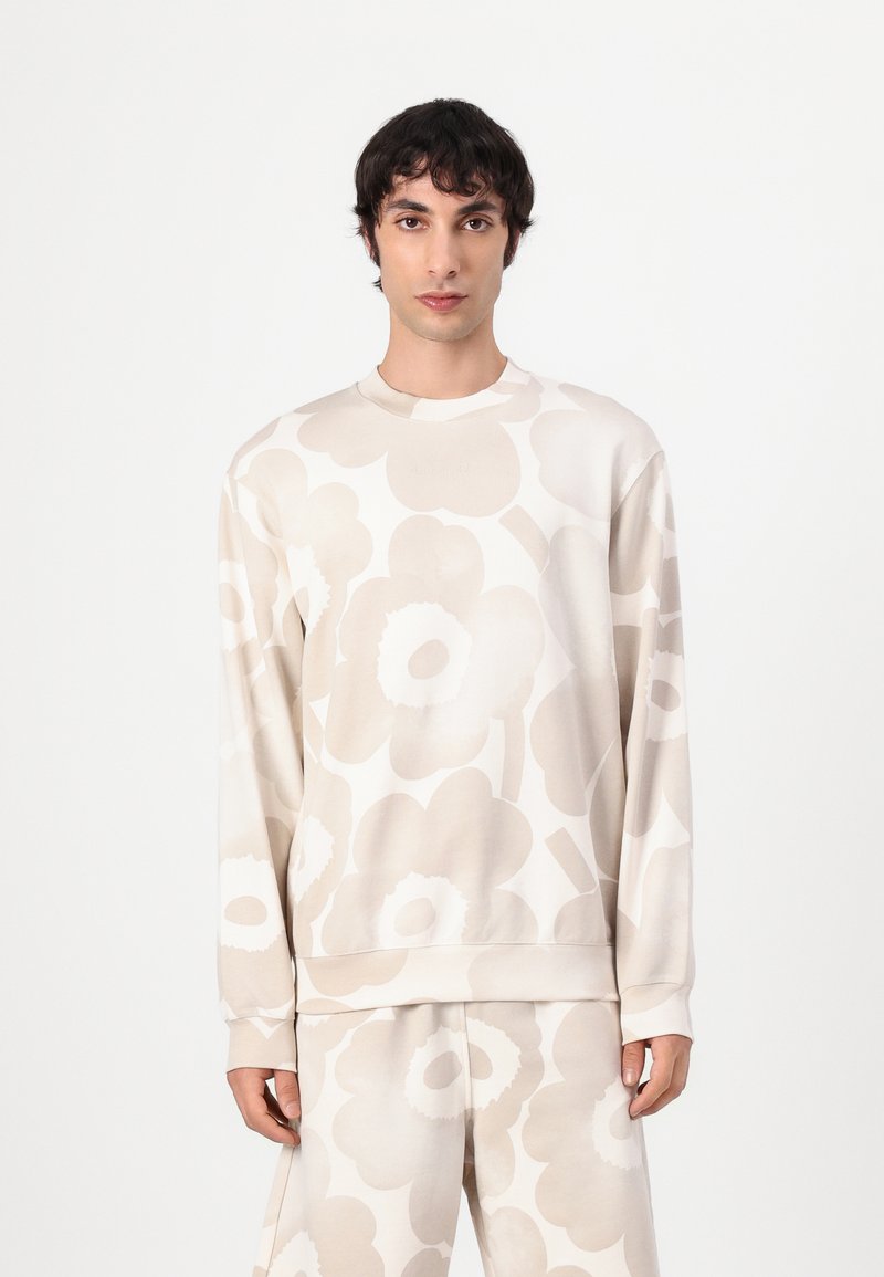 Beige Sweatshirt mit langen Ärmel, das ein großes florales Muster in helleren Farbtönen zeigt. Weicher Stoff, Rundhalsausschnitt und gerippte Bündchen.