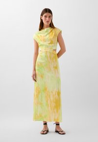 Maxi dress made of smooth fabric with a yellow and green abstract pattern. Features a high neckline and cut-out detail at the waist.