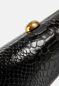 Black snake-embossed leather clutch with a glossy finish. Features a prominent gold-tone oval clasp with the brand name embossed.