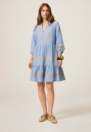 Light blue dress with a v-neck, puffed sleeves, and embroidered gold geometric patterns. Features a tiered skirt and a loose fit.