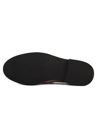 Black rubber sole with a textured grip pattern, showcasing a smooth, rounded shape and minimalistic design elements.