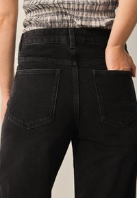 Sorte denimjeans med højtaljet design, der har et enkelt udseende, to baglommer og en glat tekstur.