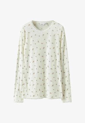 Pikendustega topp pehmes helesinises kangas, millel on pruun lilleline muster. Struktuurne viimistlus pitsi äärisega kaelaaugu ja alläärme juures.