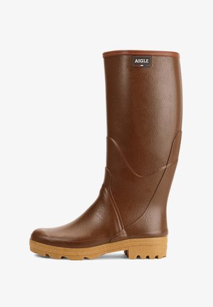 Bota de goma marrón hasta la rodilla con acabado texturizado, un logo elevado y una suela gruesa y estriada para mayor agarre. La parte superior presenta líneas curvas sutiles.