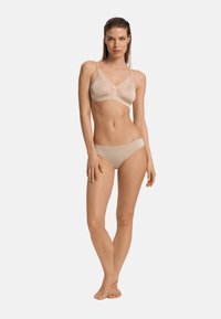 Completo di lingerie beige composto da un bralette con bordo in pizzo e uno slip abbinato, caratterizzato da un tessuto liscio e un design semplice.