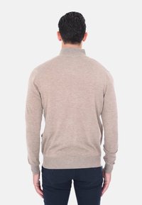 Maglione beige a maglia con colletto pieghevole e maniche lunghe. Presenta una superficie liscia e polsini a coste, progettato con una forma aderente.