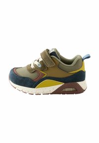 Mehrfarbiger Sneaker mit einer Kombination aus olivgrünem, braunem und gelbem Material. Mit einem Klettverschluss, kontrastierenden Schnürsenkeln und einer strukturierten Sohle.