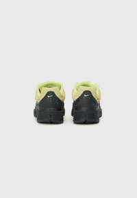 Sapatilhas Nike em amarelo e preto. Apresentam um cabedal texturizado, colarinho acolchoado e uma sola em borracha com padrões de aderência distintos.