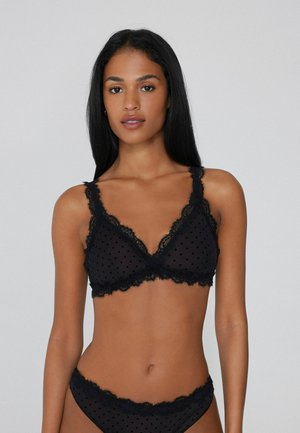 Bralette negro con encaje y topitos, con un diseño de escote en V y tirantes ajustables, acompañado de unas braguitas de encaje a juego.