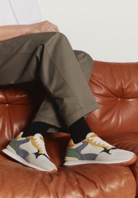 Sneaker con un mix di materiali; prevalentemente bianchi con accenti gialli, blu, verdi e arancioni. Finitura in suede testurizzato e mesh.