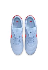 Világoskék sportcipők sima textúrával, élénk narancssárga részletekkel és fűzős kialakítással. Nike logó látható az oldalon.