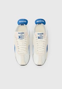 Adidași albi și blue cu șireturi, cu accente din suede și un tab de călcâi texturat albastru. Prezintă logo-ul Reebok pe limbă.