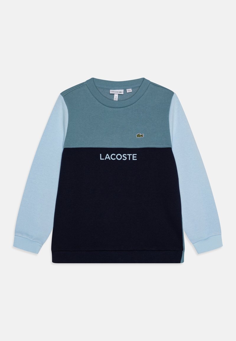 Sweat-shirt à manches longues col rond avec manches bleu clair, partie supérieure sarcelle, bas noir, texte "LACOSTE" et logo crocodile sur la poitrine.