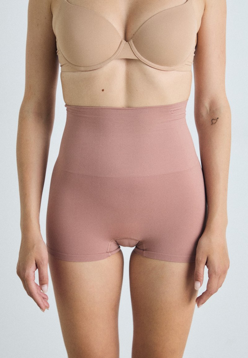 Shorts modellati a vita alta, di un rosa chiaro, senza cuciture, realizzati in un tessuto elasticizzato. Presentano una texture liscia e una cintura sottile per il massimo comfort.