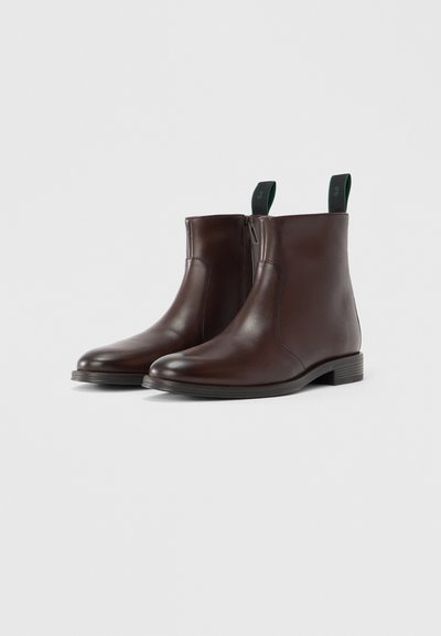 Braune Leder-Stiefeletten mit glatter Oberfläche, seitlichem Reißverschluss und grünem Zuglasche. Niedriger, gestapelter Absatz und abgerundete Zehendesign.