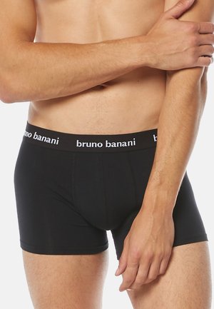 Schwarze Boxer-Shorts aus Stretchbaumwolle mit einem elastischen Bund, der mit weißem Text bedruckt ist. Glatte Textur und figurbetontes Design.
