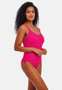 Lyst pink, mønstret heldragt badedragt med justerbare snore i siderne og tynde skulderstropper. Glat tekstur.